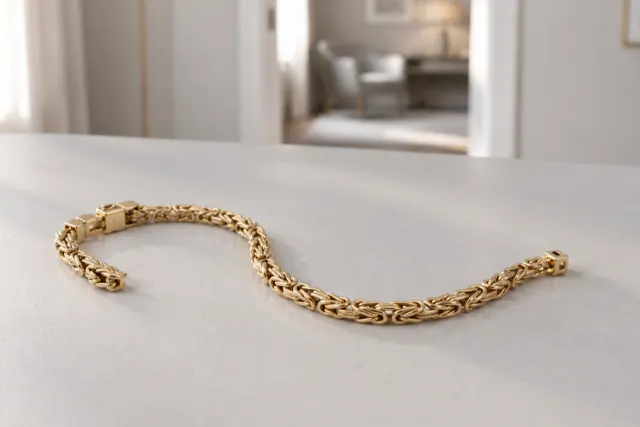 Kejsarlänk armband i guld som ligger på ett ljust bord