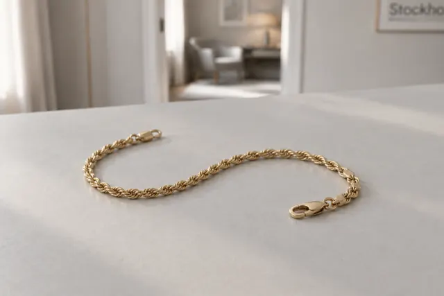 Kordellänk armband i guld som ligger på ett ljust bord