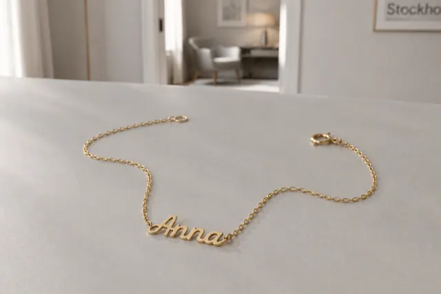 Namnhalsband i guld som ligger på ett ljust bord