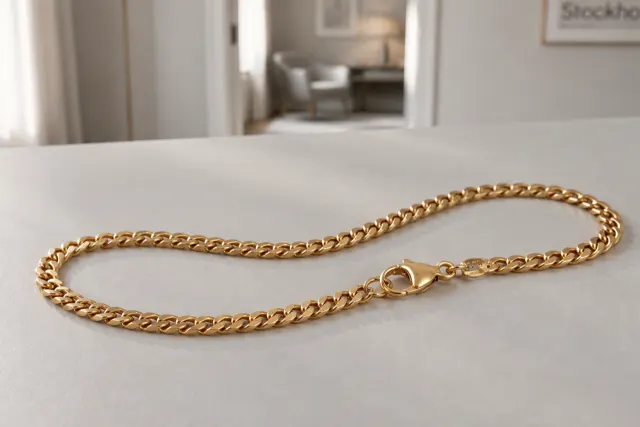 Pansarlänk halsband i guld som ligger på ett ljust bord